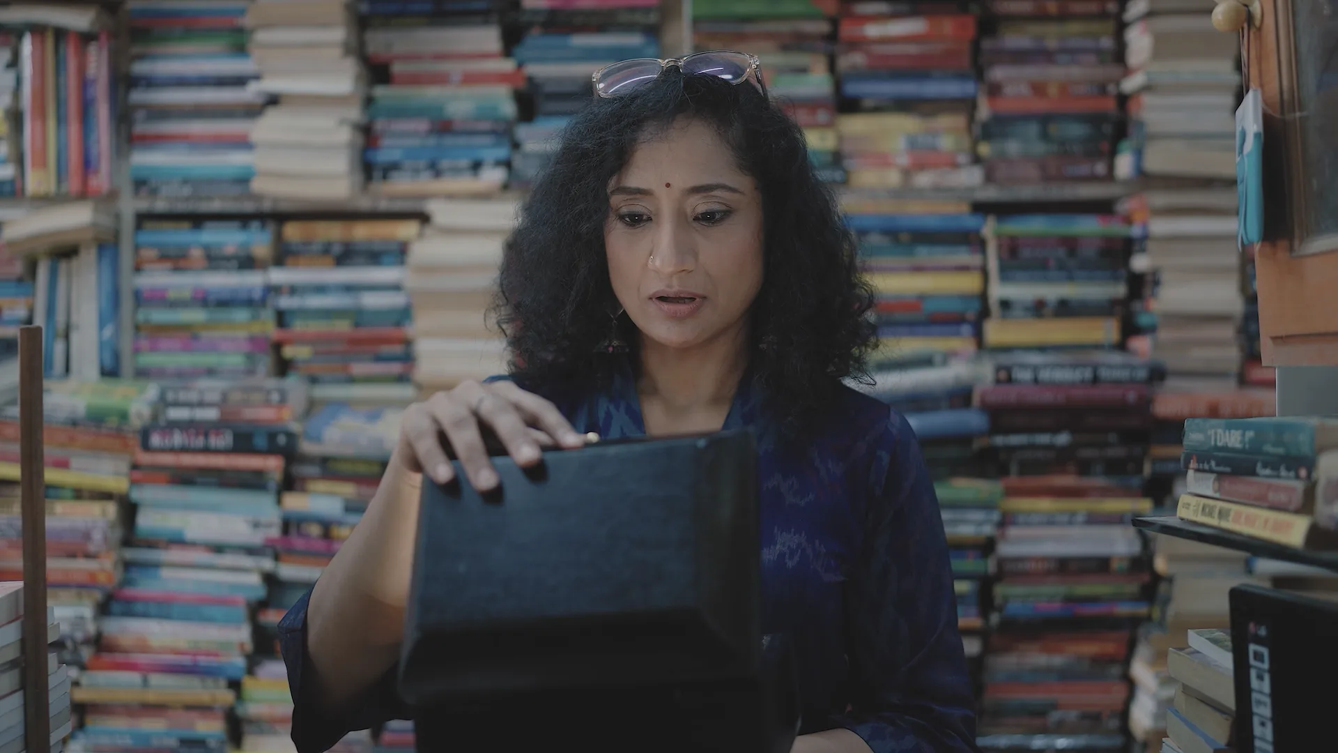 Mugdha Raj in her bookshop, opening a black box among stacked books