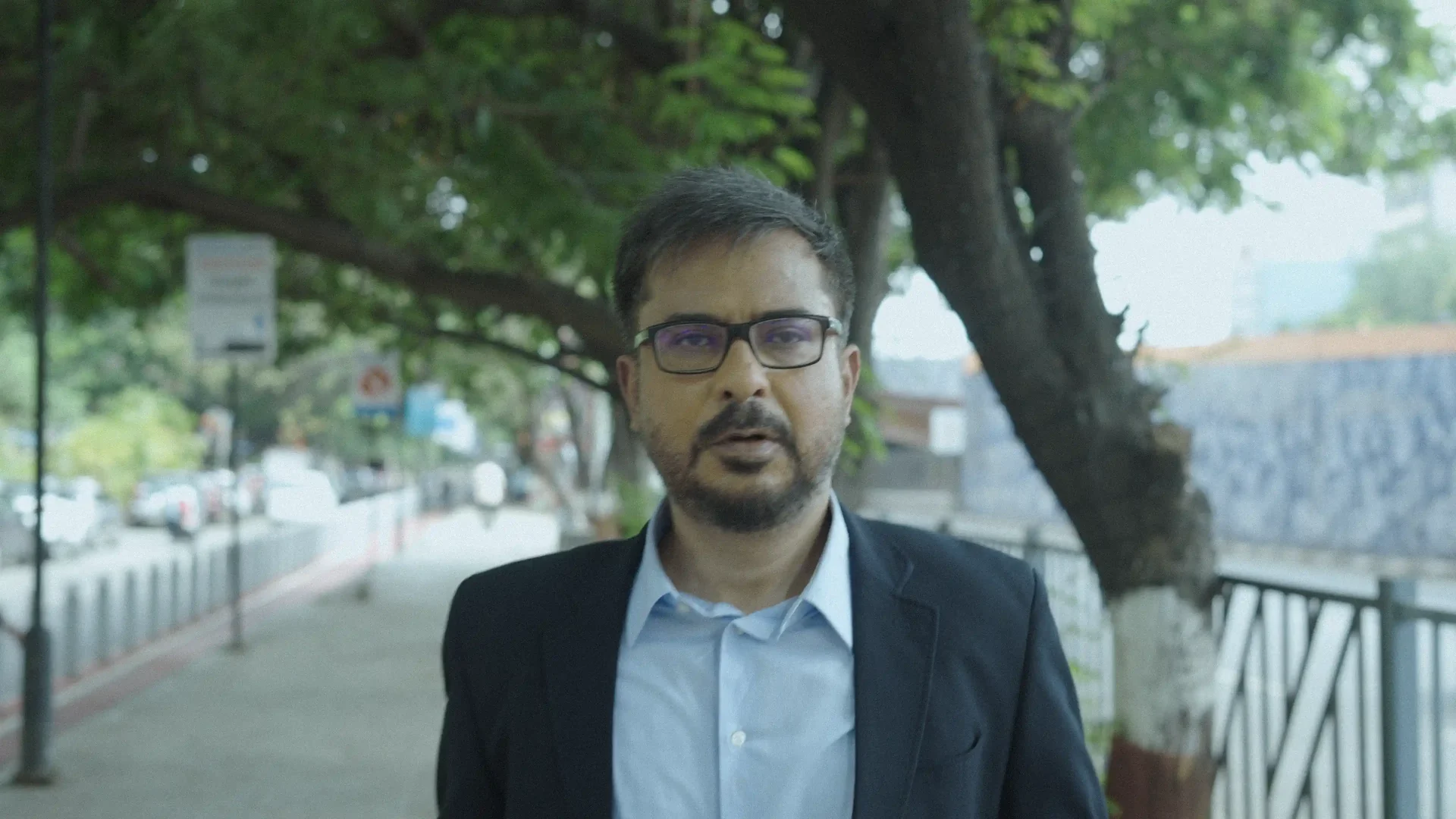 Anand Simir as Simir on a tree-lined street in Mumbai