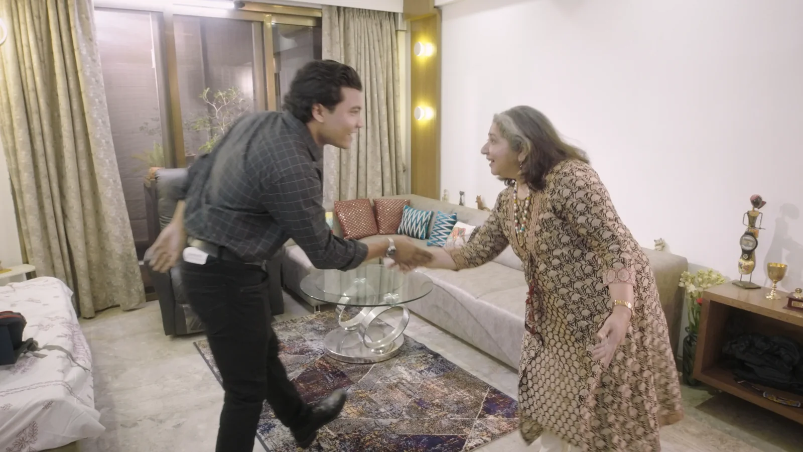 Iswar Mohan shakes hands in the apartment living room