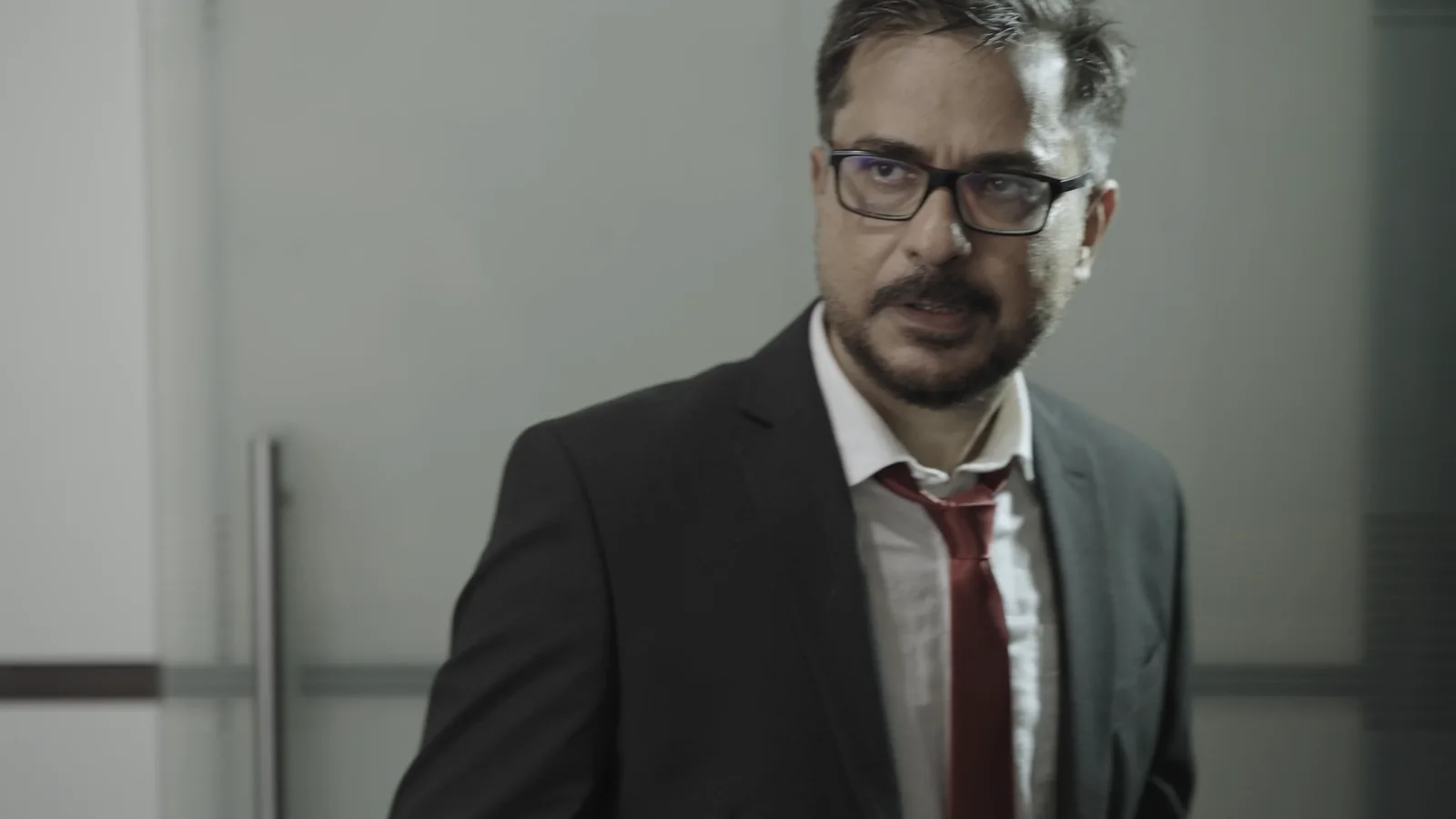 Simir in a dark suit and loosened red tie